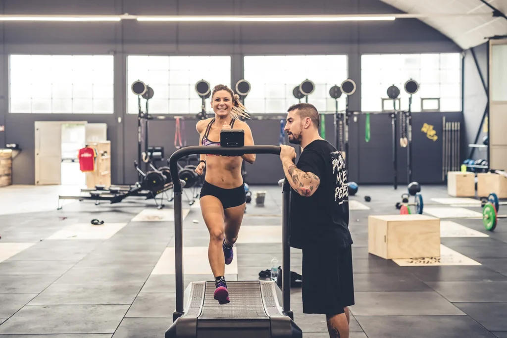 athletic woman running on treadmill with trainer